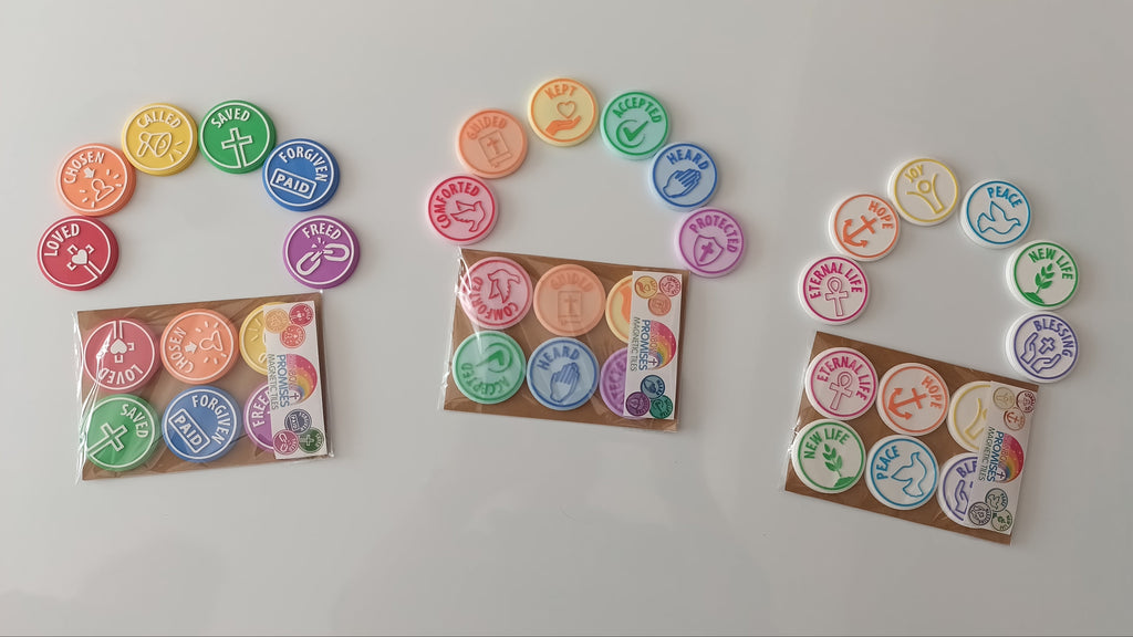 Three small packages of colorful round charm beads or stickers arranged on a plain white background. Each package contains multiple circular pieces in different colors with printed symbols and text, and three matching loose pieces are displayed above each package.