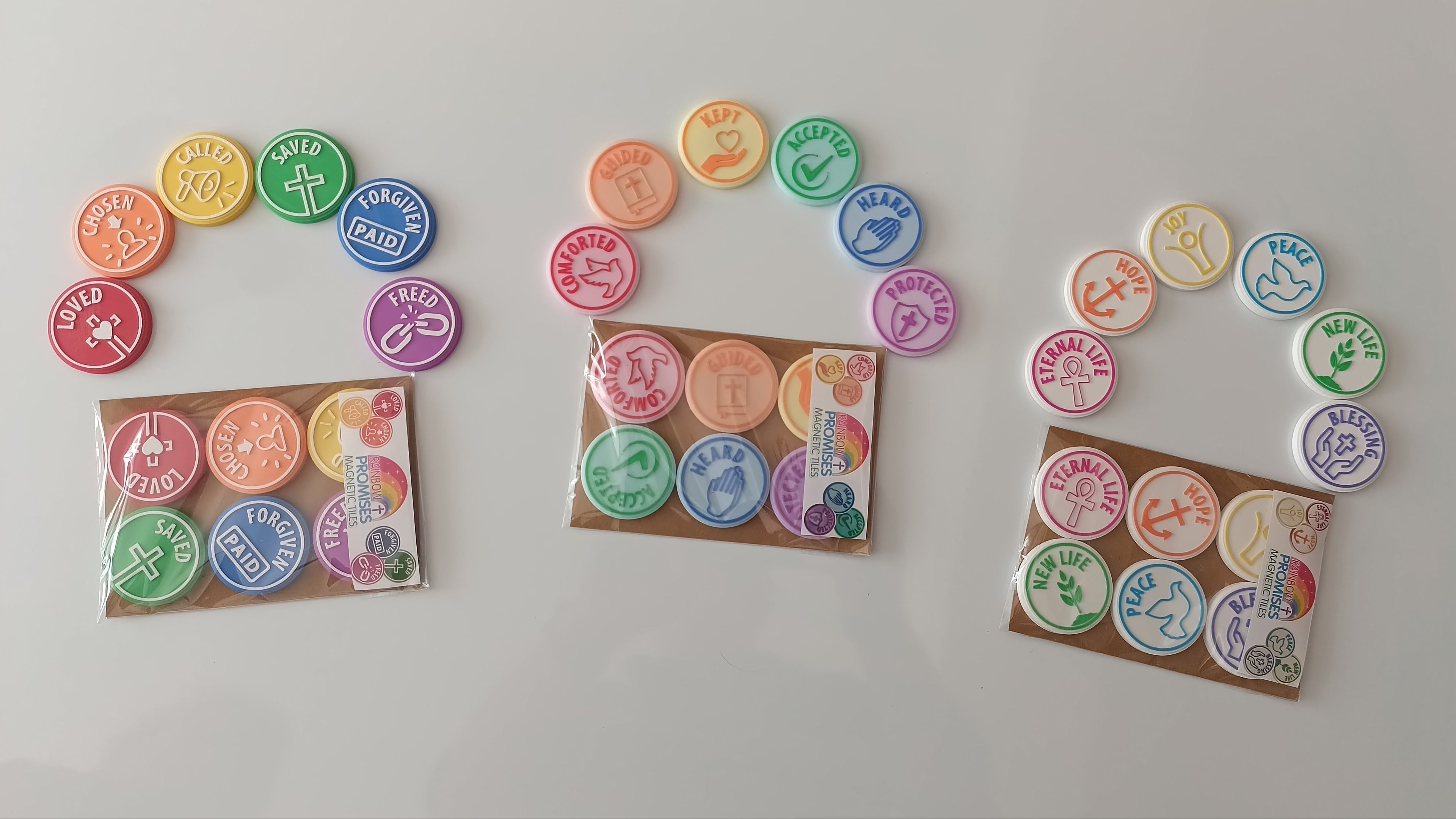 Three small packages of colorful round charm beads or stickers arranged on a plain white background. Each package contains multiple circular pieces in different colors with printed symbols and text, and three matching loose pieces are displayed above each package.